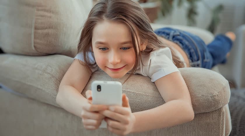 Un enfant joue avec un téléphone portable sur le canapé.