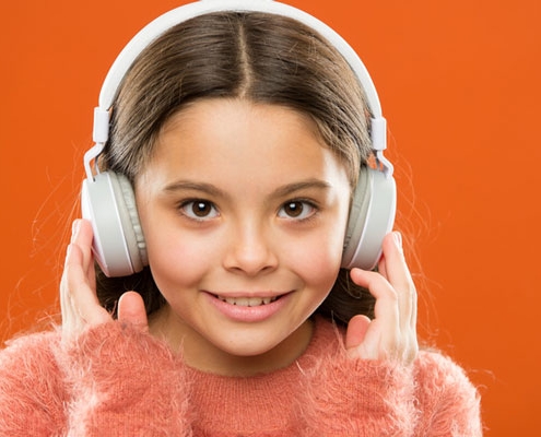 Ein junges Mädchen mit Bluetooth-Kopfhörern auf dem Kopf.