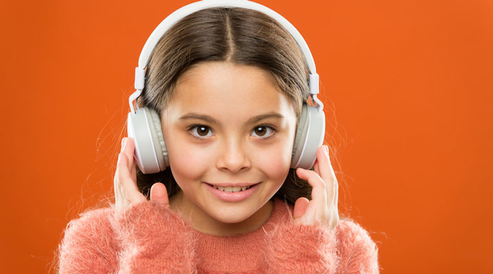 Ein junges Mädchen mit Bluetooth-Kopfhörern auf dem Kopf.