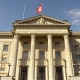 Das Bundeshaus in Bern mit Schweizer Flagge auf dem Dach.