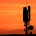 Ein Mobilfunkmast zeichnet sich als Silhouette vor einem orangefarbenen Himmel ab.