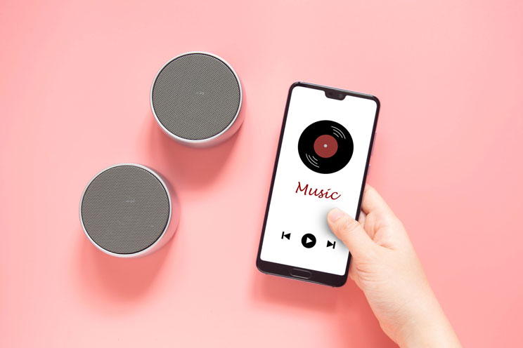 Une main tient un smartphone avec un lecteur de musique dessus.