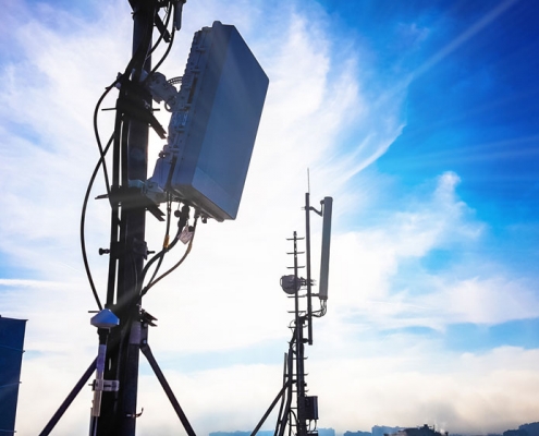 Deux pylônes de téléphonie mobile 5G avec un ciel bleu derrière eux.