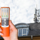 Ein Cemprotec 34 Elektrosmog-Messgerät vor einem Haus mit Handy-Antenne.